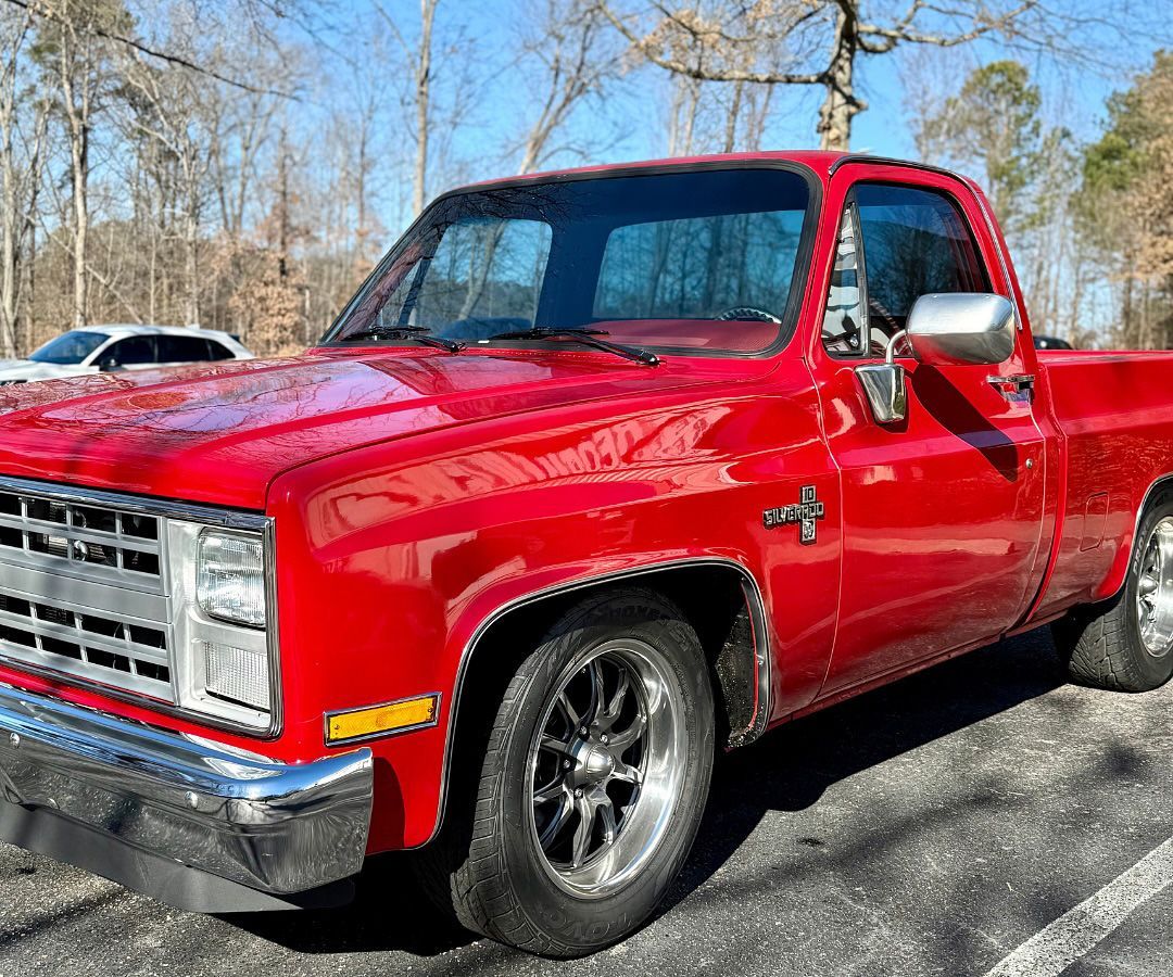 Red Chevrolet pickup truck parked outdoors on a sunny day.