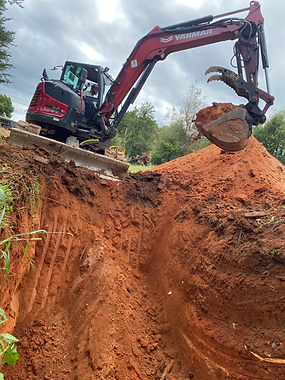 A red excavator is digging a hole in the dirt.