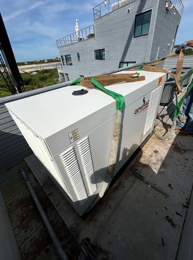 White generator on rooftop being secured with green straps; building in background.