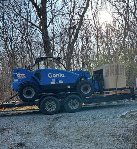 A genie forklift is being transported on a trailer.