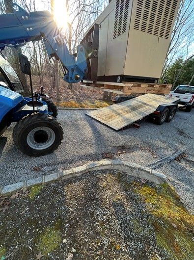 A tractor is loading a trailer with a large building on it.