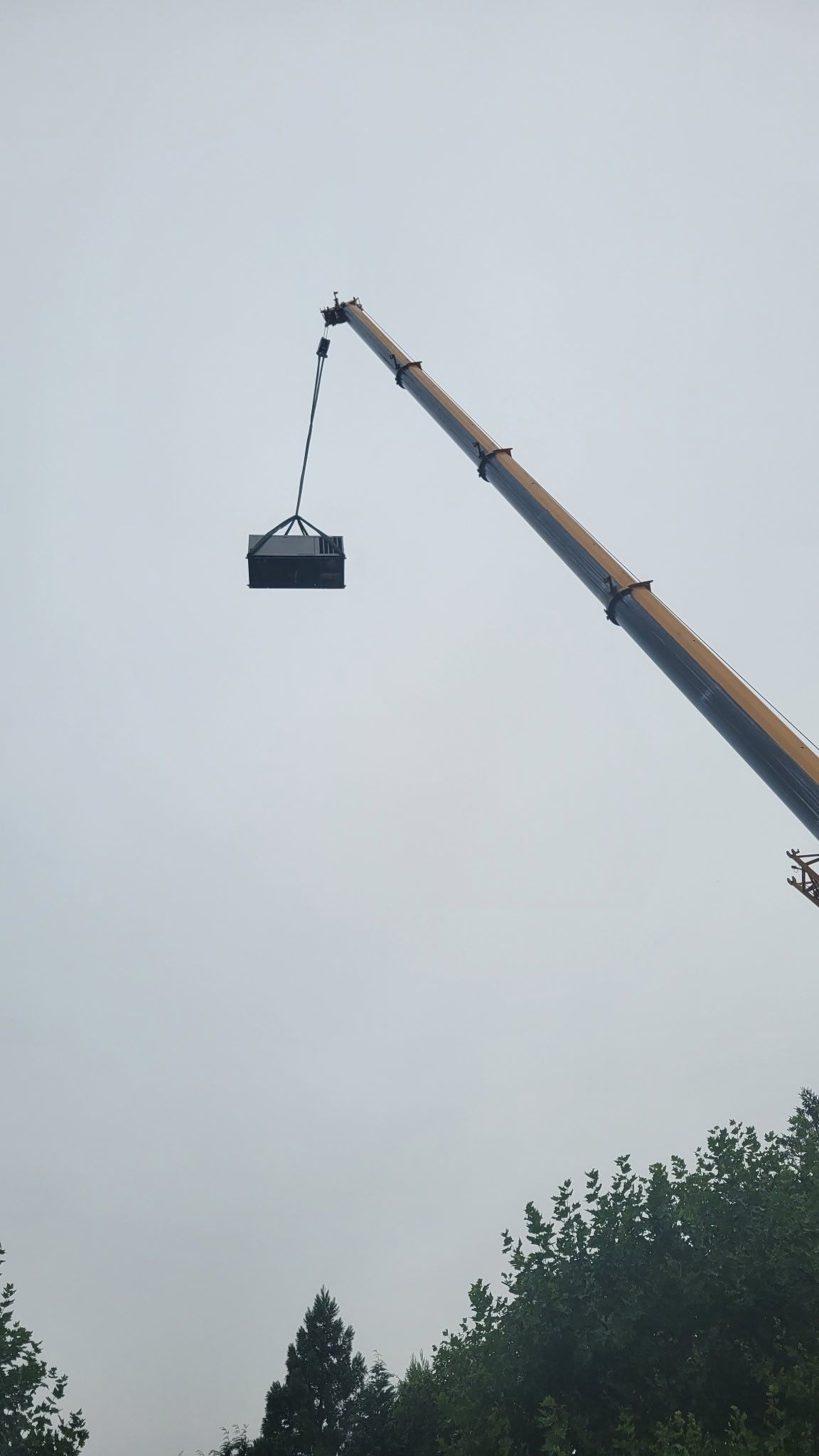 A crane is lifting a container in the air