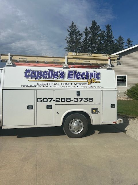 White Capelle's Electric truck with logo and phone number parked in front of a house.