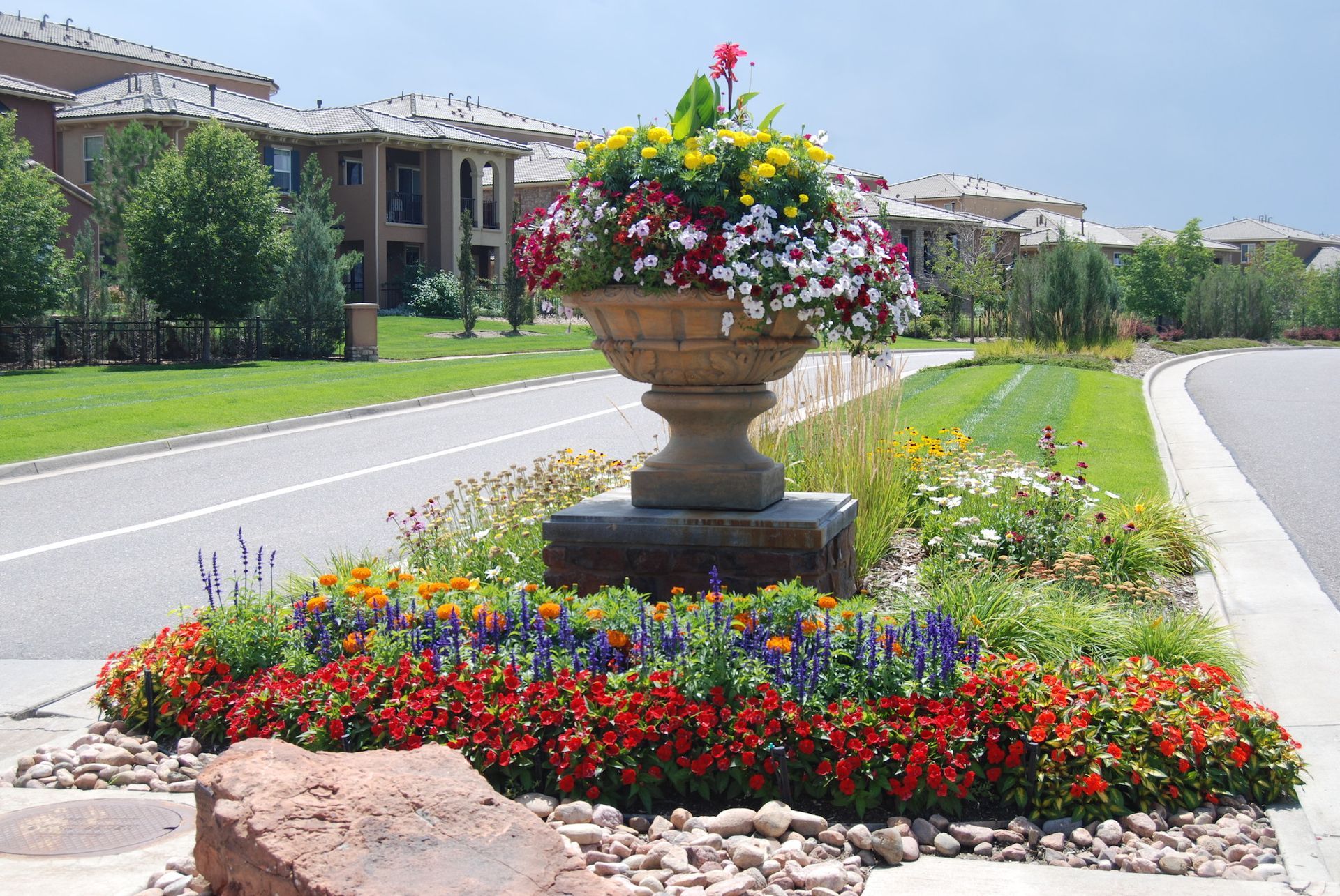 A planter filled with flowers sits on the side of the road