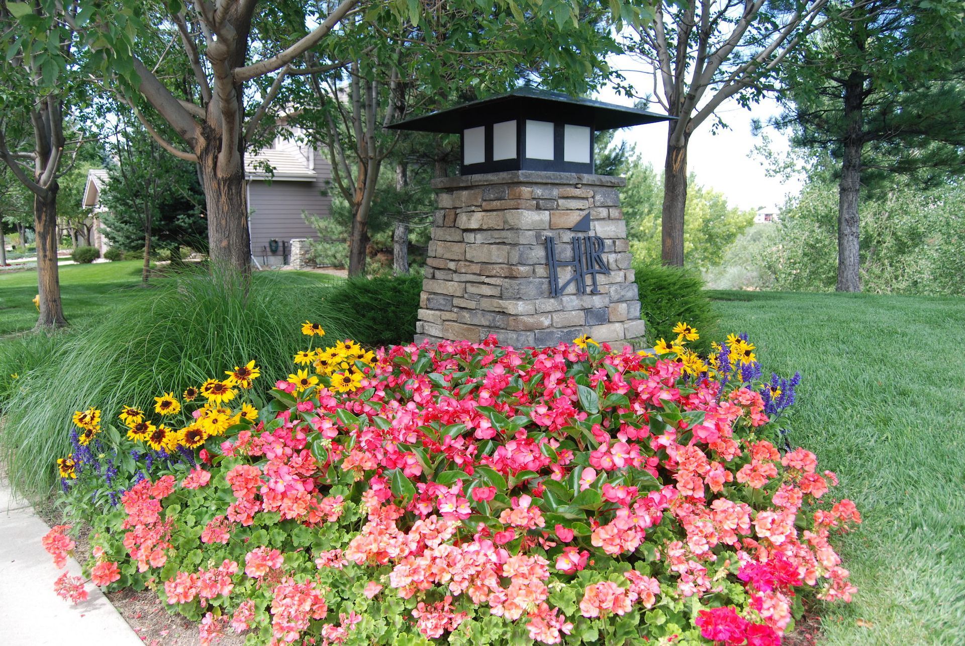 A stone pillar surrounded by flowers and a sign that says vhc