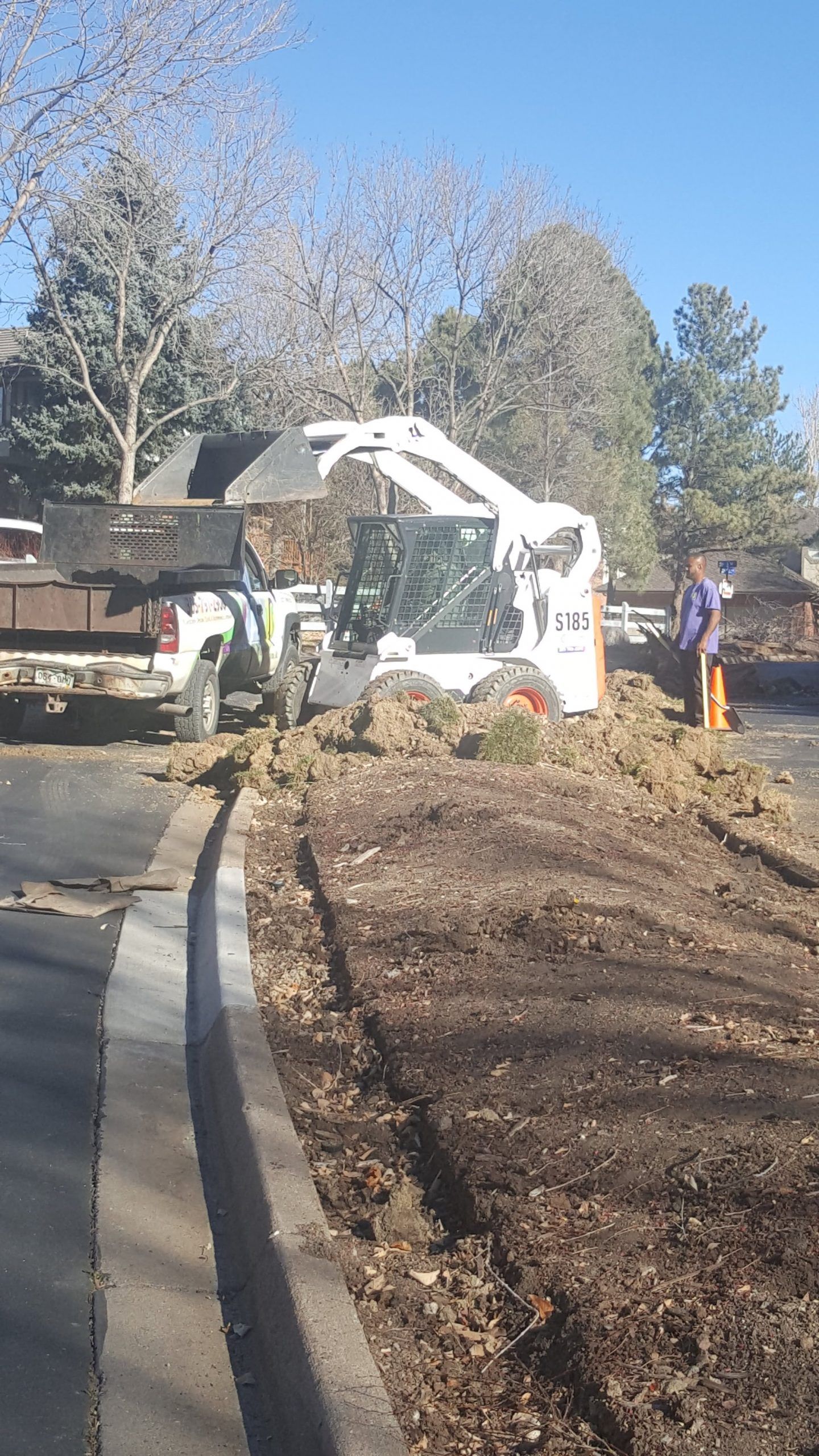 A man is standing next to a bulldozer on the side of a road.