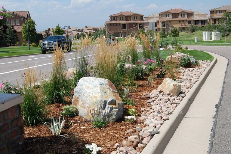 A car is parked on the side of the road next to a rock garden