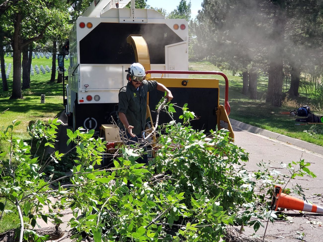 A man is standing in front of a tree chipper