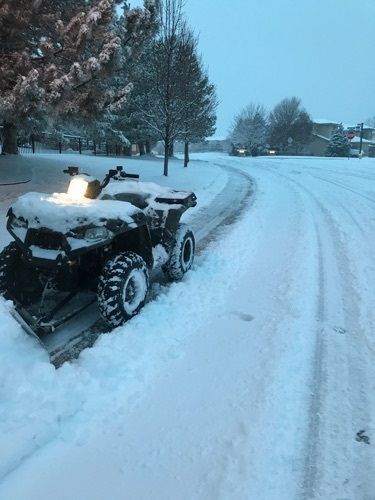 An atv is parked in the snow on the side of the road.