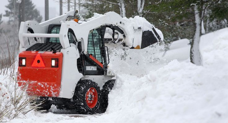 A snow plow is clearing snow from the side of a road.