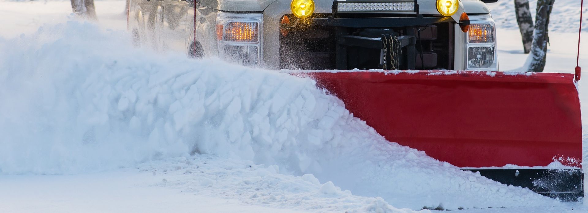 A snow plow is clearing snow from the side of a road.