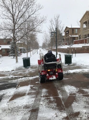 A person is riding a lawn mower on a snowy street.