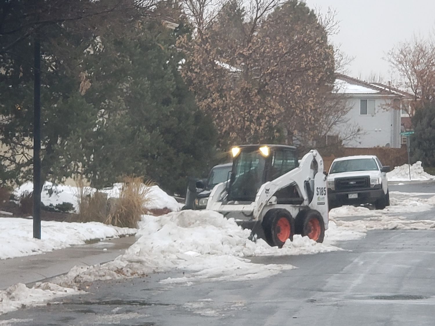 A bobcat is clearing snow from the side of the road