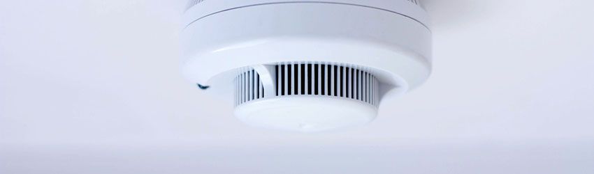 White smoke detector mounted on a ceiling