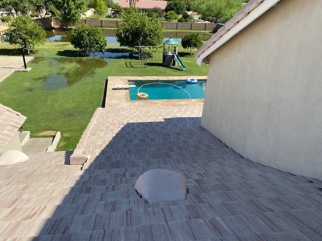 Backyard patio with a pool, lawn, and children’s playset on a sunny day