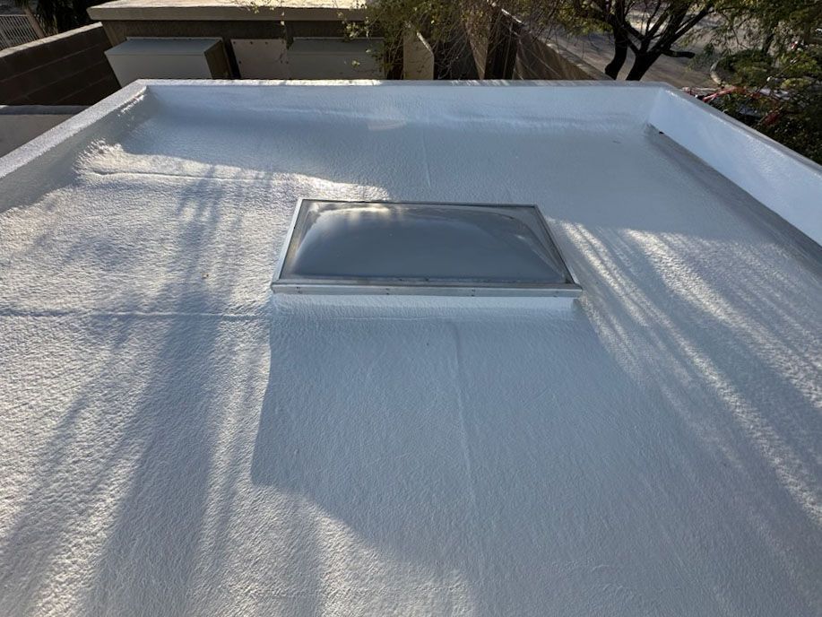 Flat white rooftop with a central skylight under dappled tree shadows