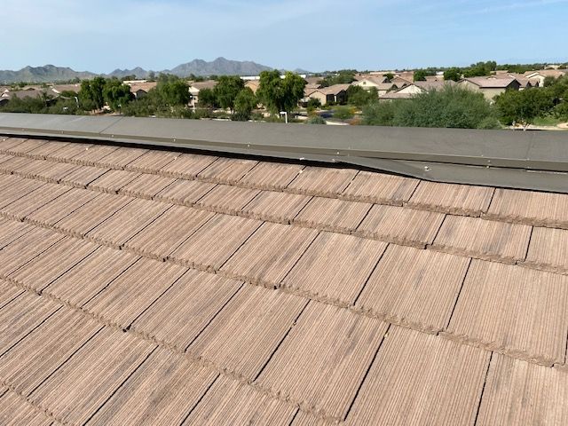 Brown shingled roof with a clear sky and distant mountains in the background