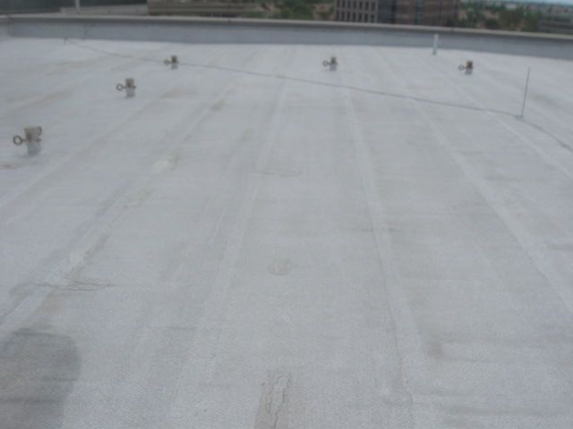 Snow-covered rooftop with several small antennas along the top edge under a gray sky