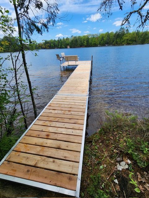 A wooden dock leading to a lake with a boat on it