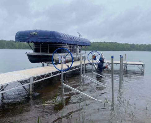 A pontoon boat is docked at a dock on a lake