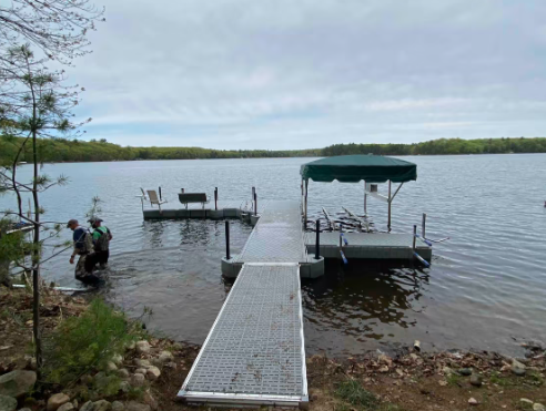 A dock on a lake with a green canopy