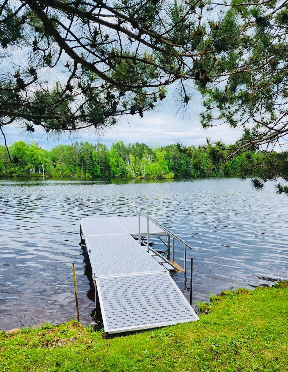 A dock is sitting on the shore of a lake surrounded by trees.