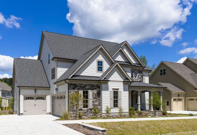 Modern gray two-story suburban house with garage and front porch under a blue sky