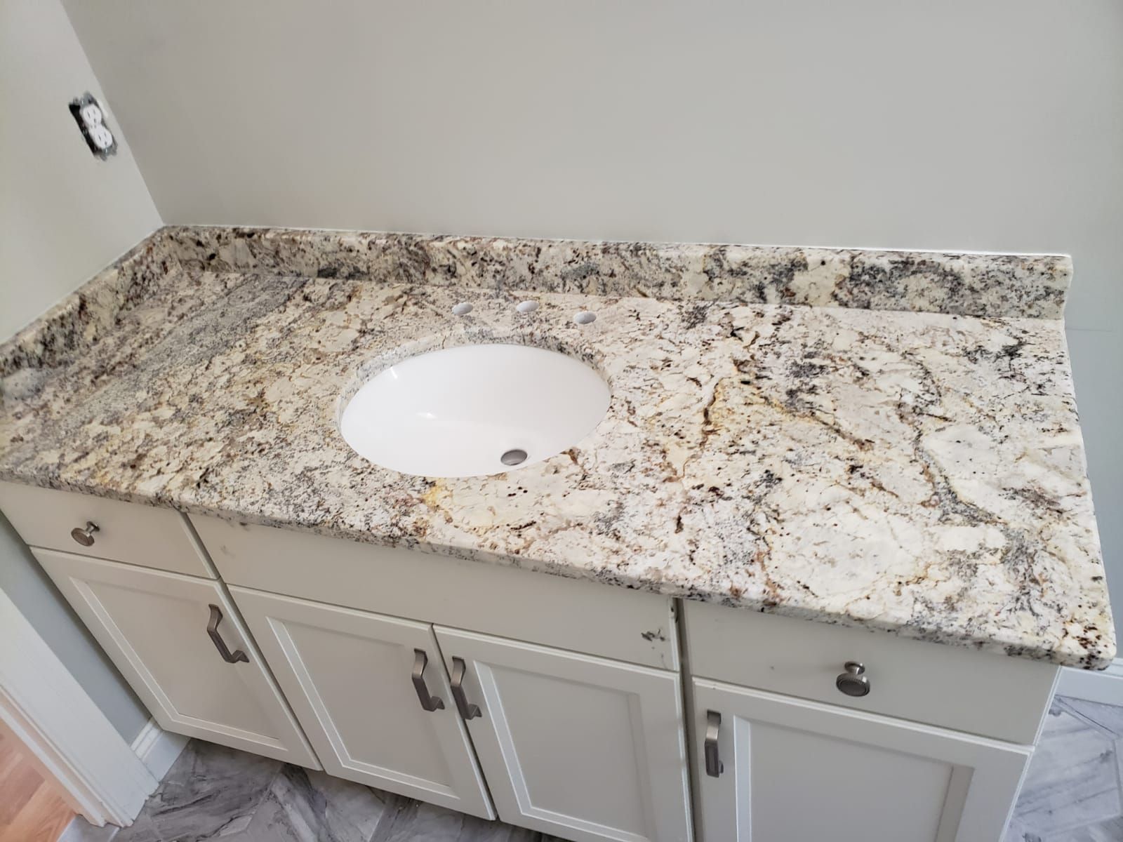 Cream-colored bathroom vanity with a granite countertop and oval sink.