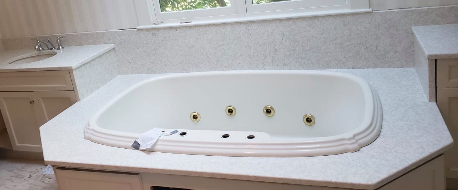 A bathroom with a white bathtub, white cabinets, and a window above.