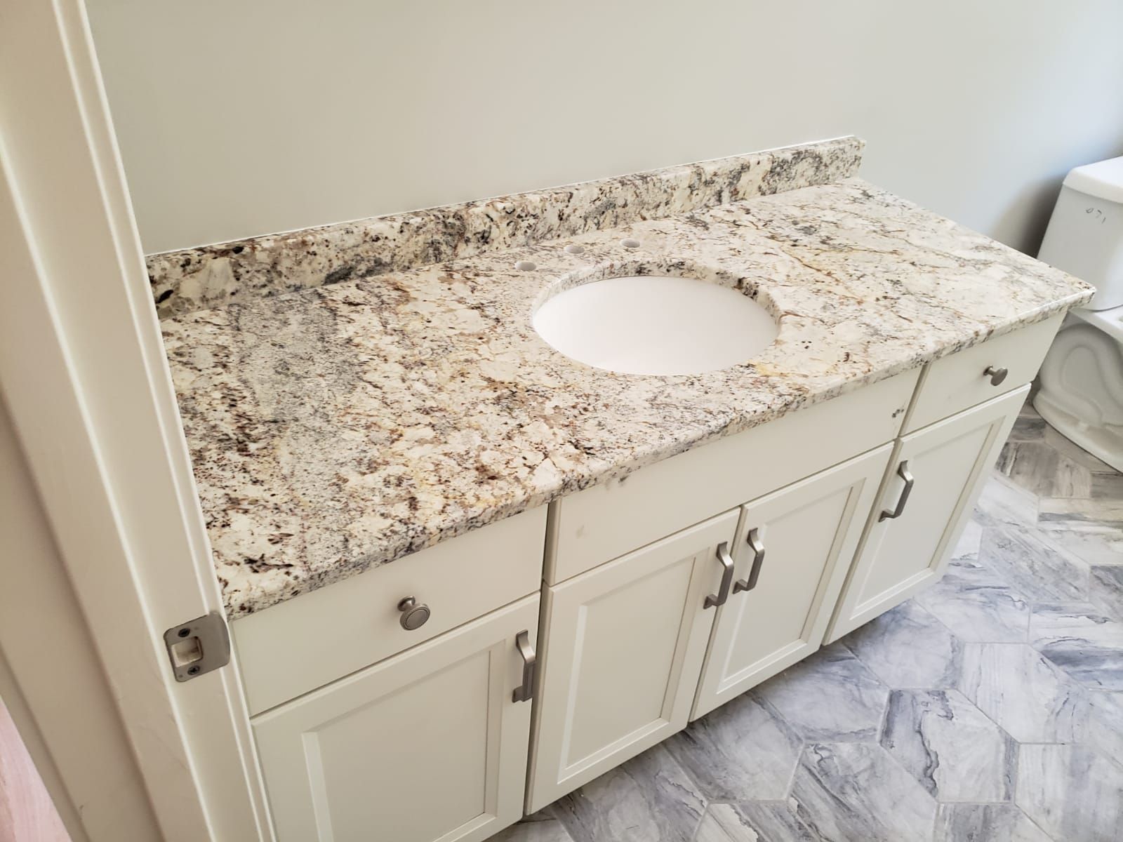 Bathroom vanity with granite countertop and white cabinets.