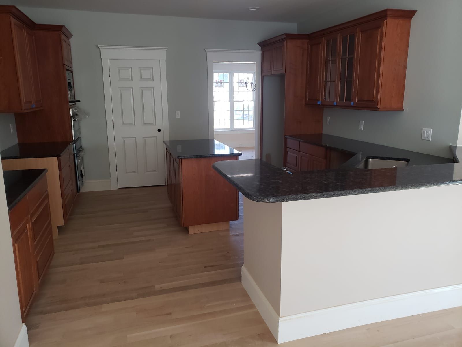 Kitchen with wood cabinets, granite countertops, and light wood flooring.