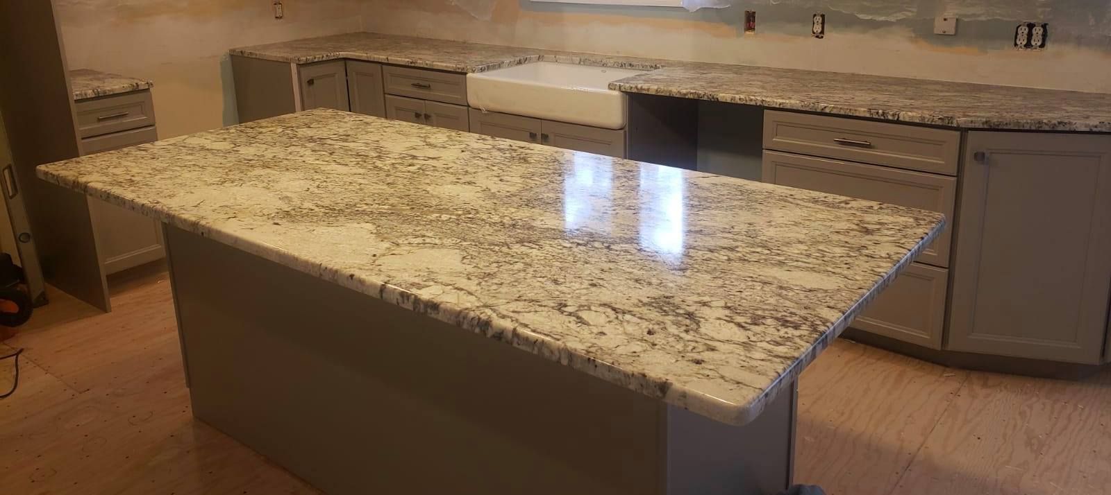 A newly renovated kitchen featuring granite countertops, gray cabinets, and a central island.