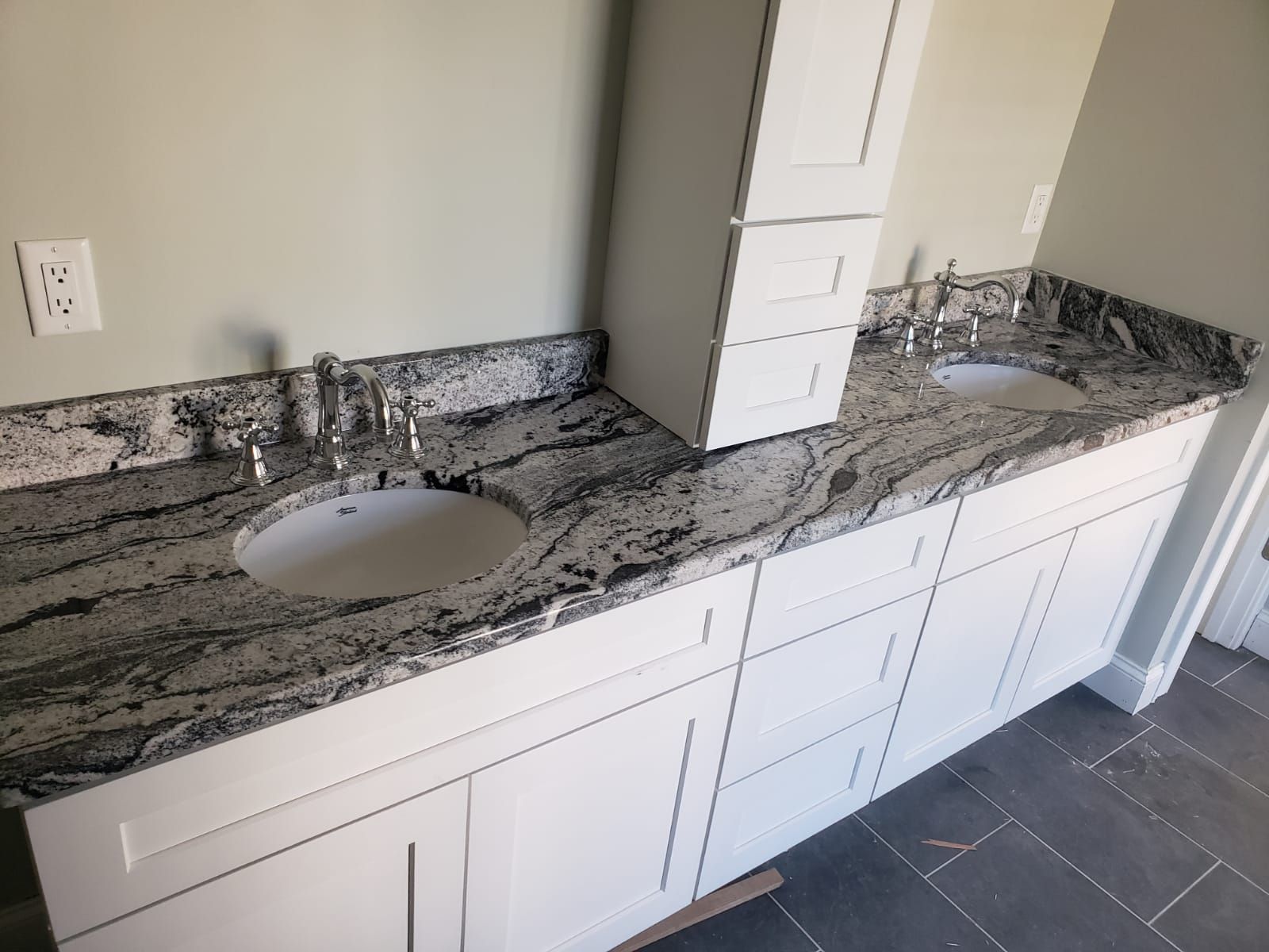 White vanity with two sinks and a granite countertop in a bathroom.