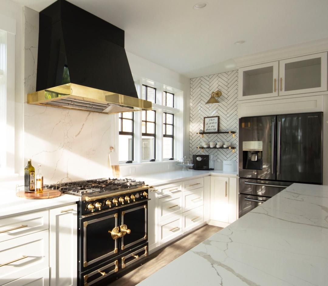 Elegant kitchen with black and gold accents, marble countertops, and a stylish range.