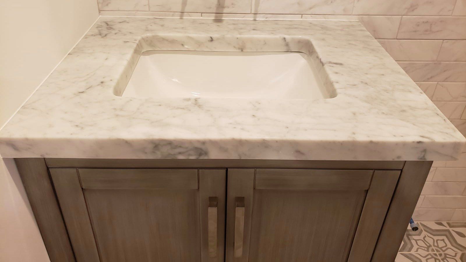 Gray bathroom vanity with marble countertop and integrated sink.