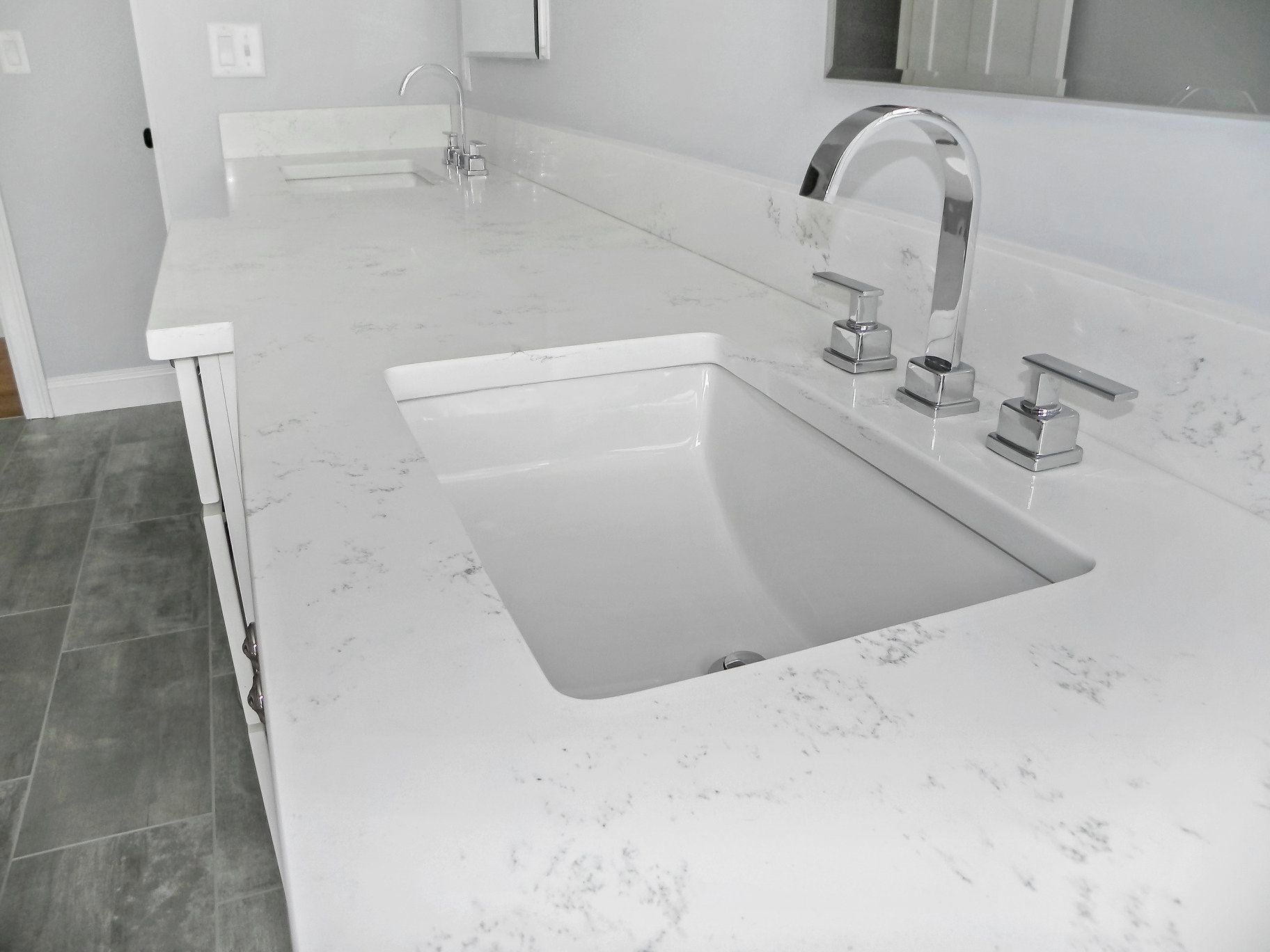 White bathroom vanity with a rectangular sink and chrome faucet.