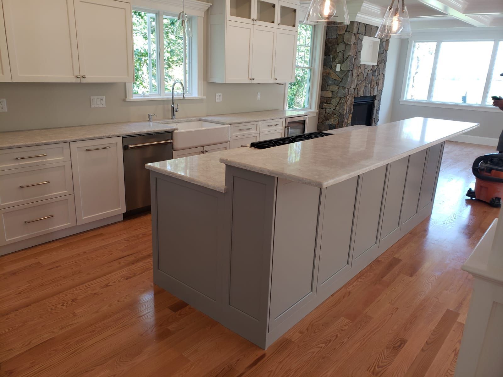 Modern kitchen with white cabinets, gray island, and hardwood floors.