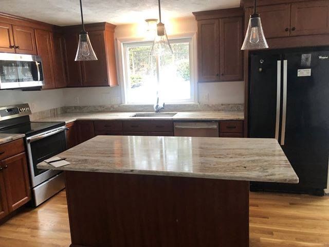Kitchen with brown cabinets, granite countertops, stainless steel appliances, and an island.