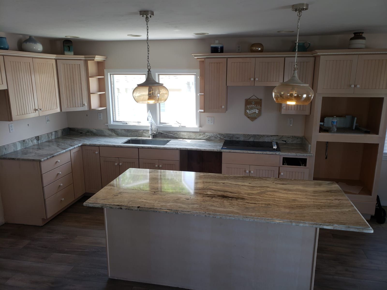 Kitchen with light-colored cabinets, granite countertops, and an island with pendant lights.