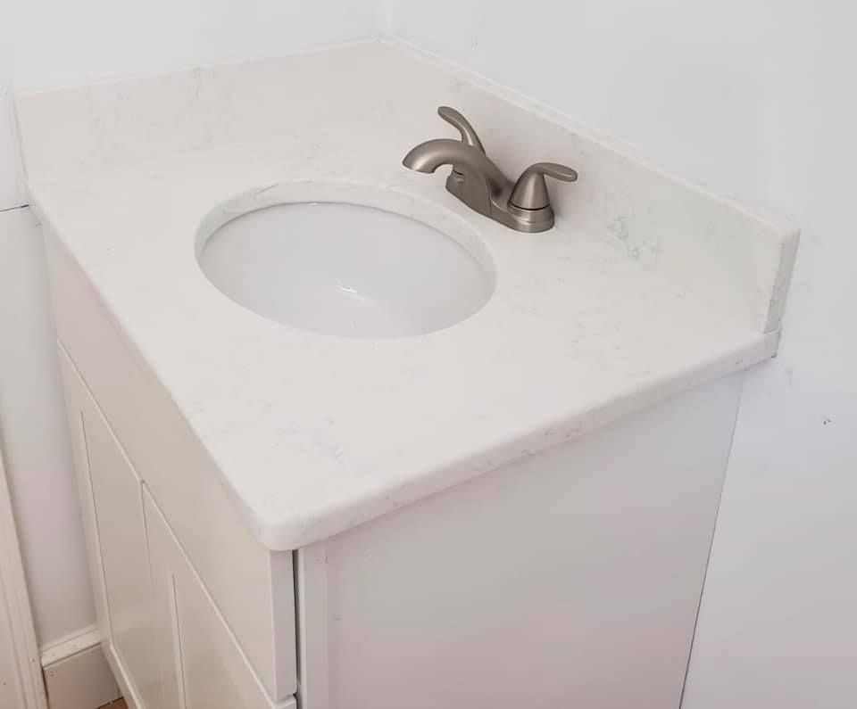 White bathroom vanity with a sink and faucet.