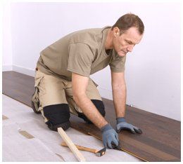 worker installing wood parquet board during flooring