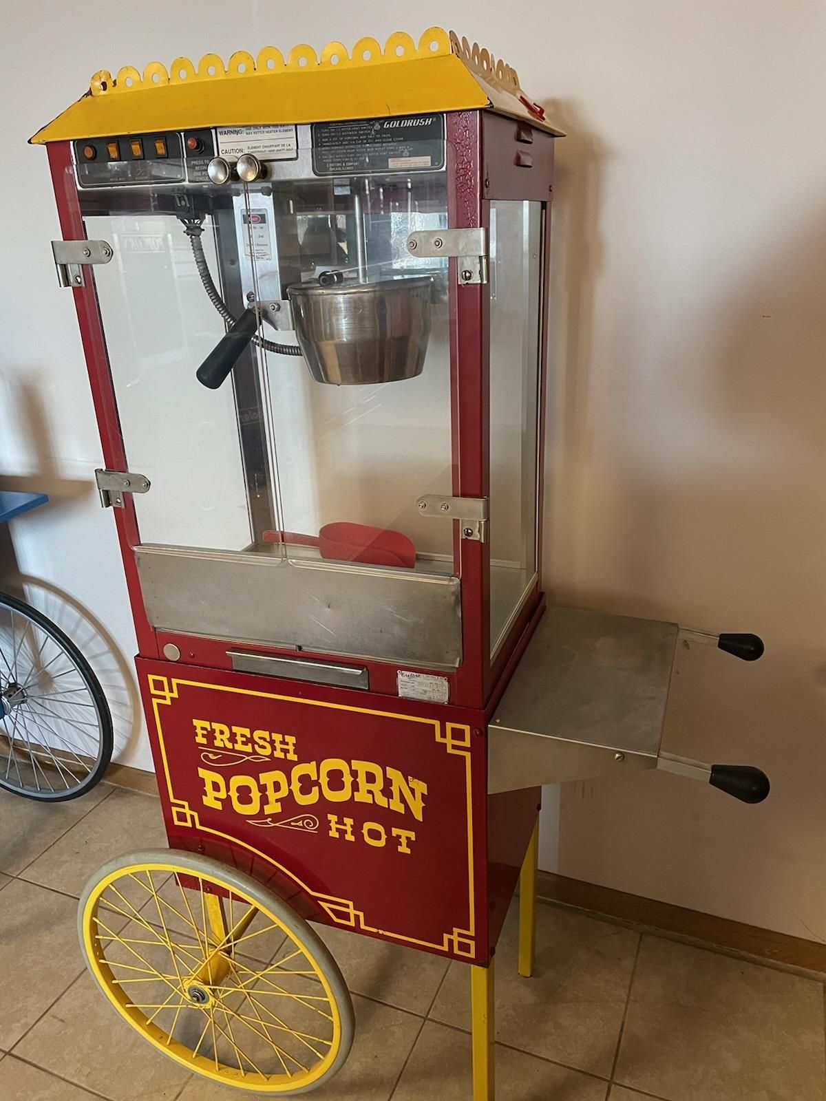 A red and yellow popcorn machine that says fresh popcorn hot