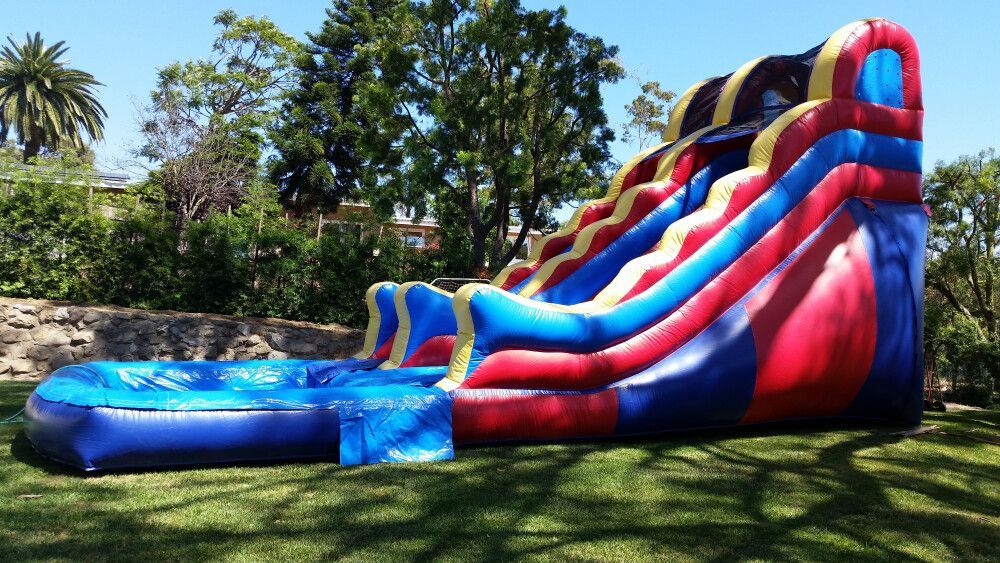 A large inflatable water slide is sitting on top of a lush green field.