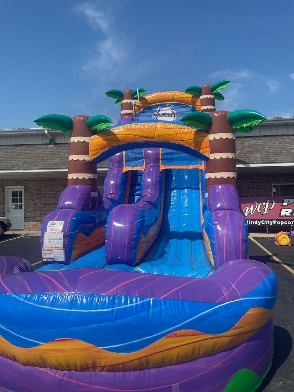 A purple and blue inflatable water slide with palm trees
