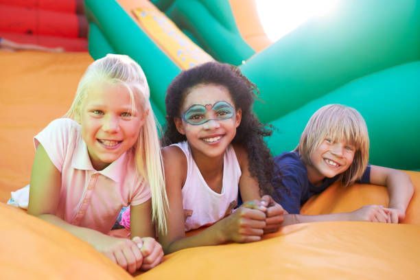 A group of children are laying on top of an inflatable slide.