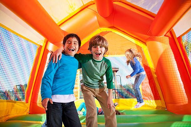 Two young boys are standing in an inflatable bouncy house.