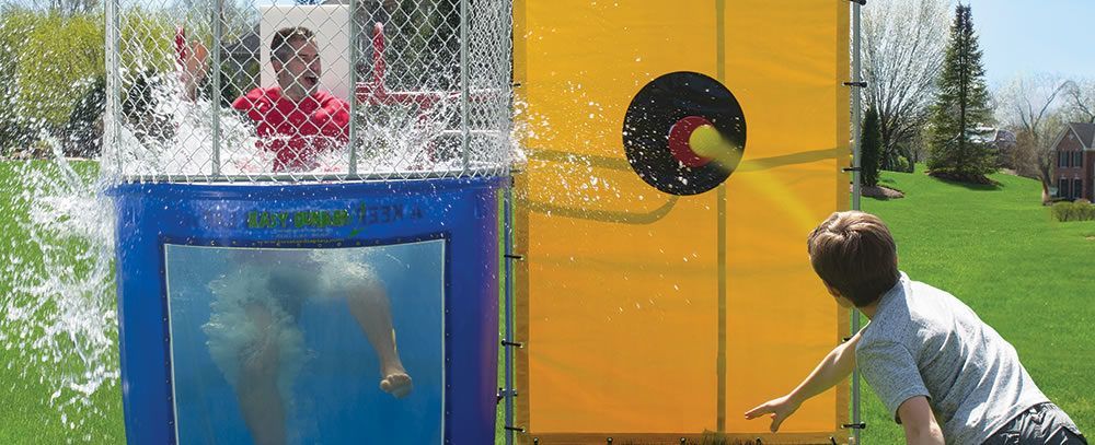 A man is throwing a tennis ball into a water bucket.