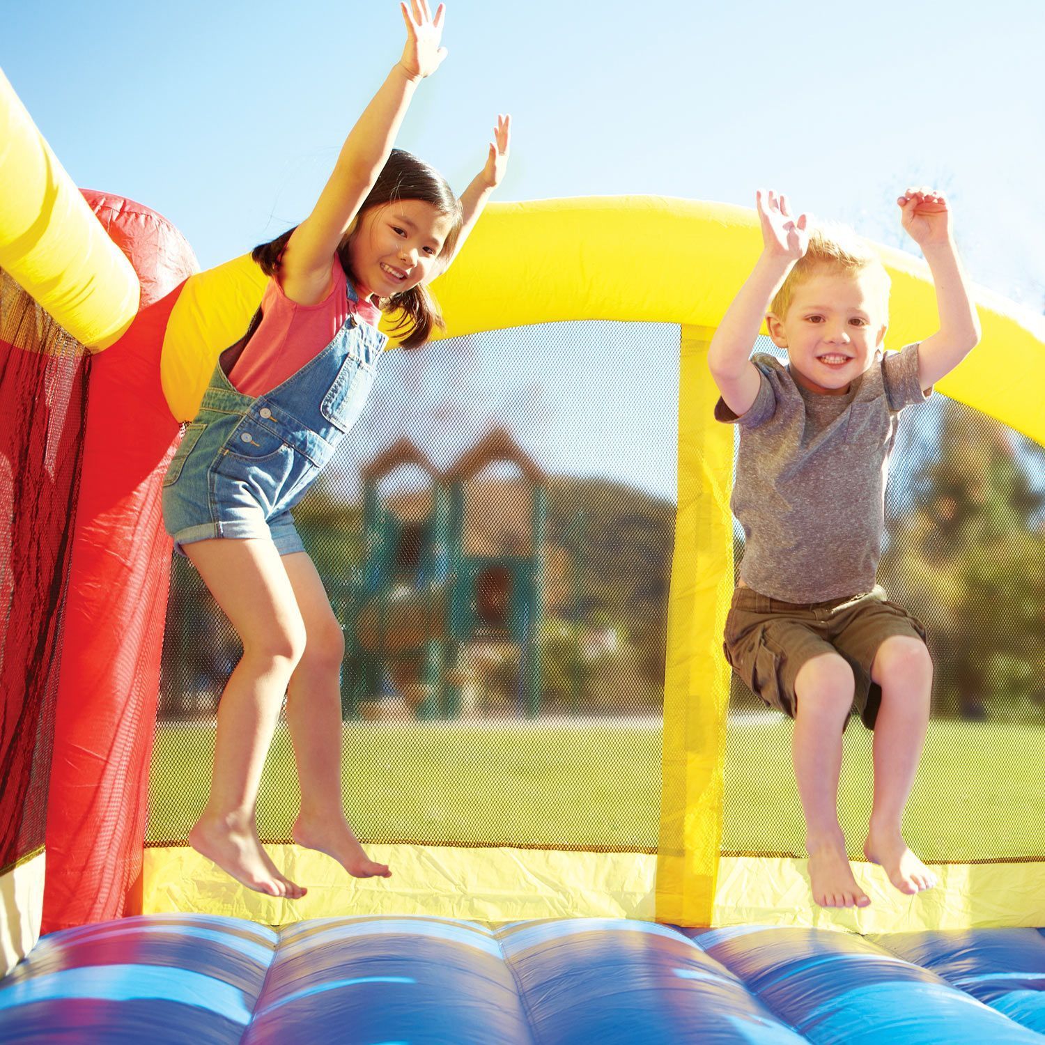 A boy and a girl are jumping on a bouncy house