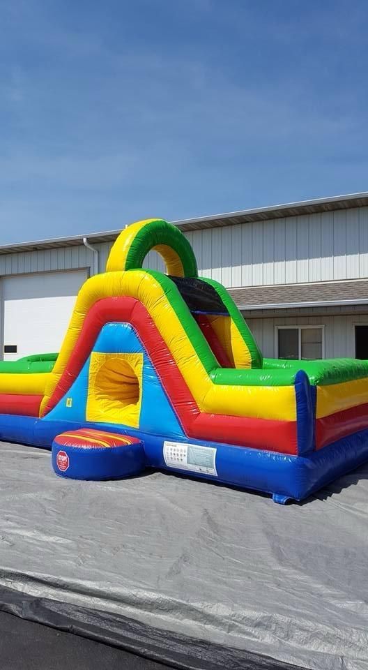 A colorful bouncy house is sitting on the side of the road in front of a building.