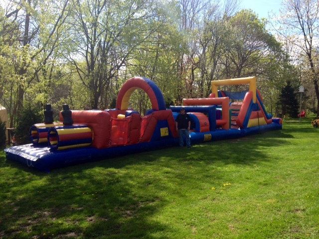 A man is standing in front of a large inflatable obstacle course.